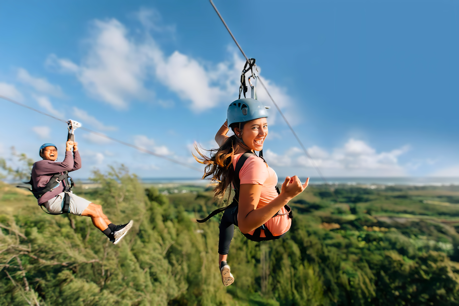 two people zipling side by side over trees