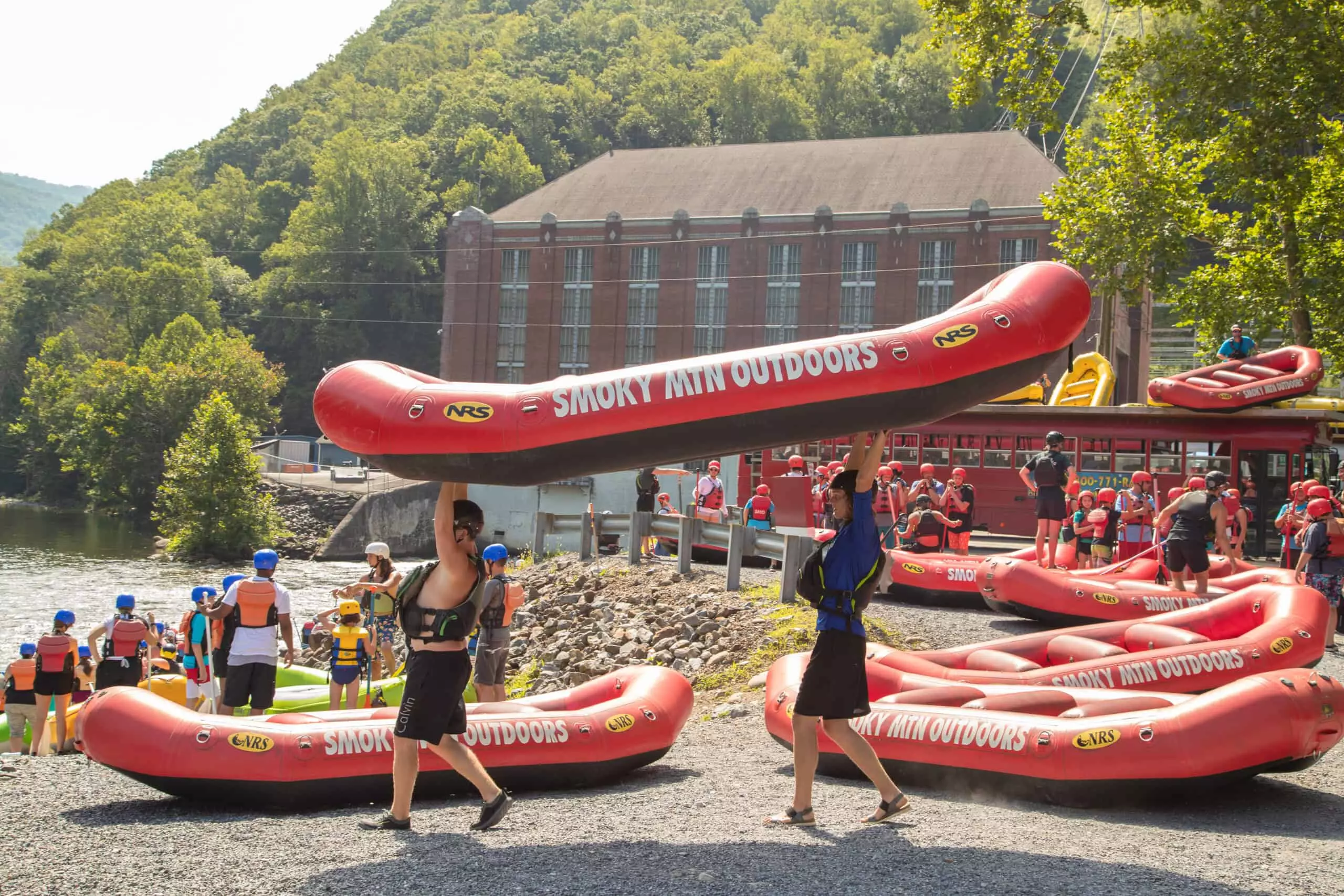 guides carrying red whitewater rafts to river