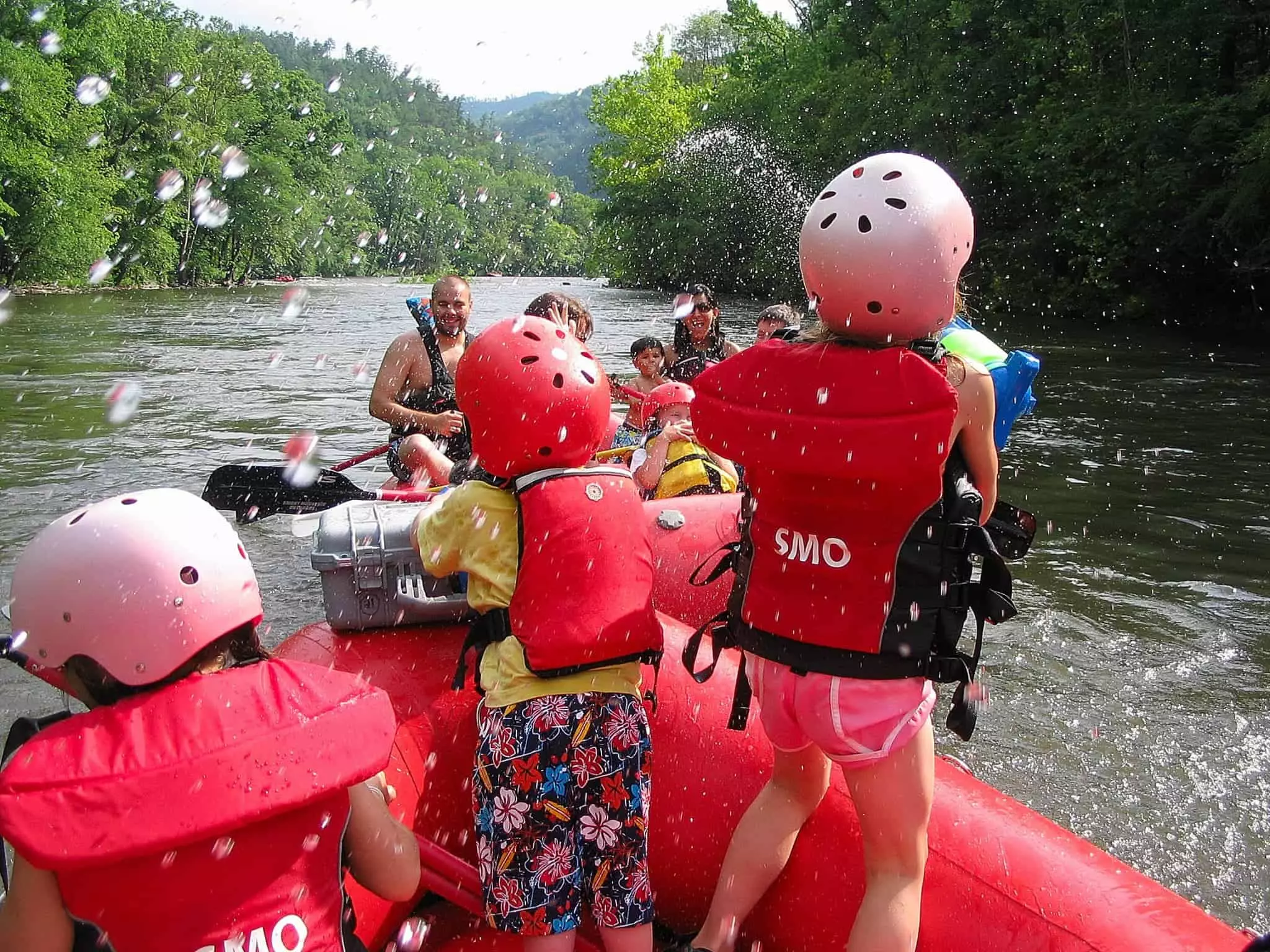Kids on a raft having water fight with family in second raft with Smoky Mountain Outdoors