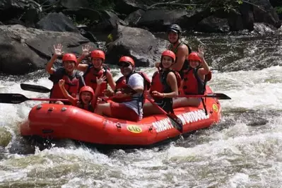 Family waving at camera while rafting