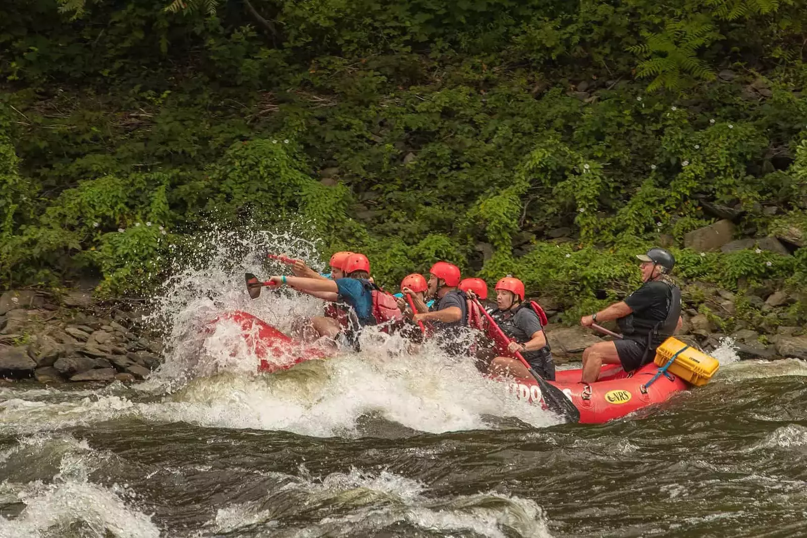 raft going over rapids and getting splashed with a big wave
