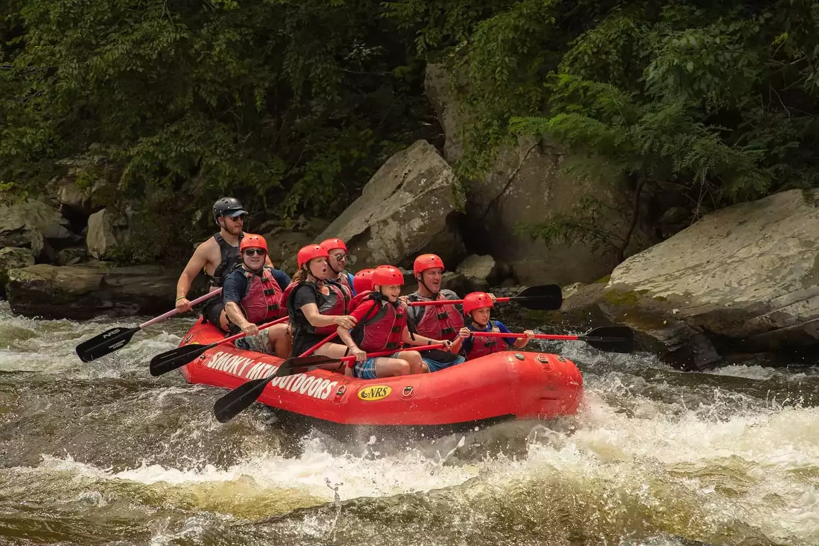people paddling in whitewater raft over rapids