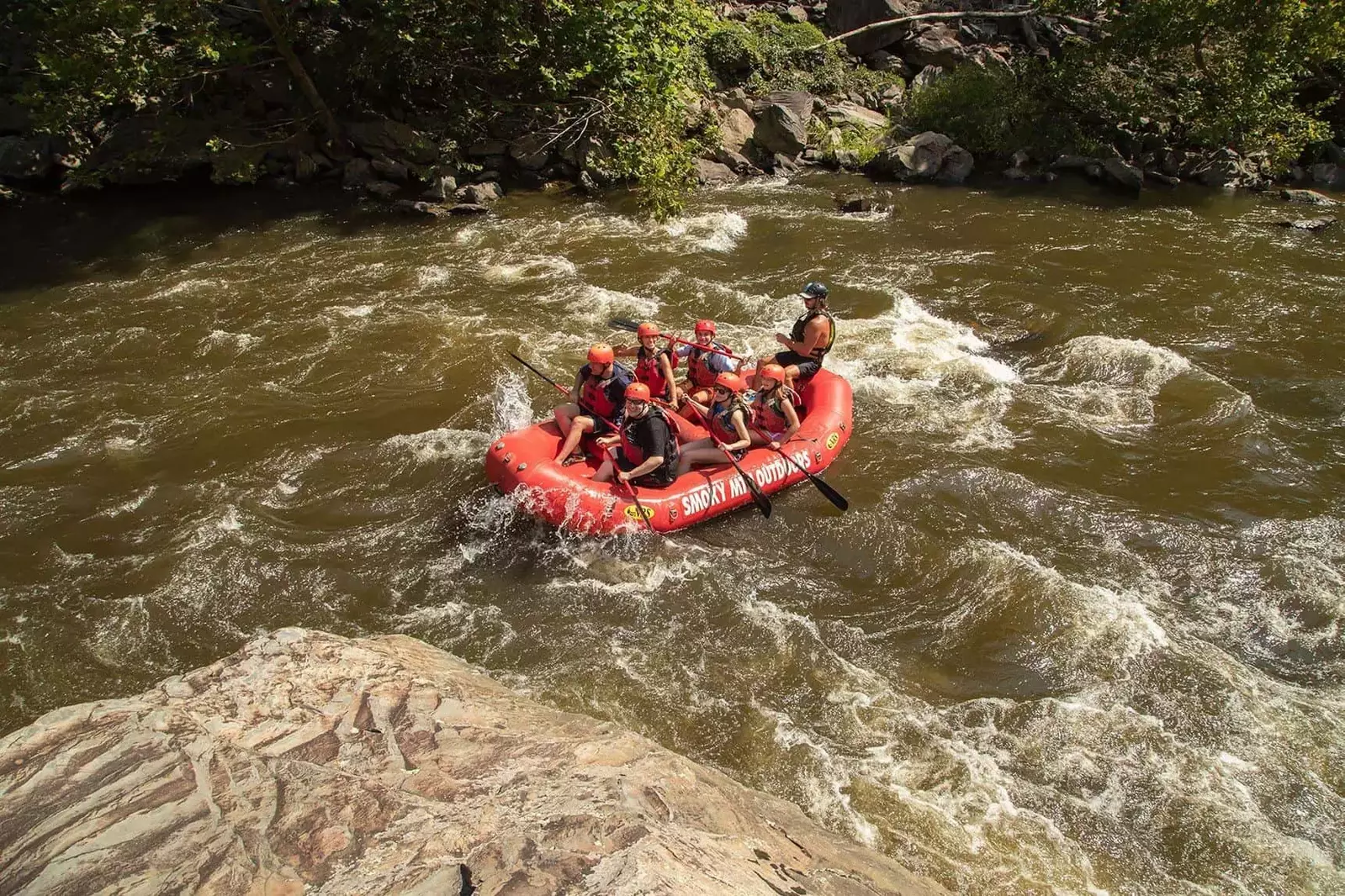 whitewater going over mild rapids around large rock