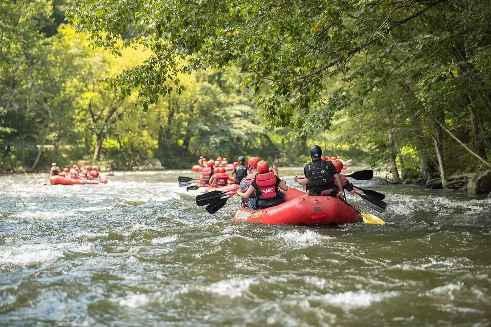 group of whitewater rafts floating down gentle rapids