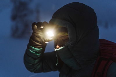 winter hiker turning on headlamp