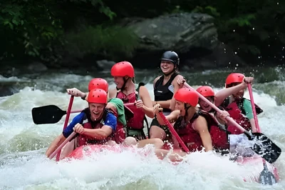A happy group of friends white water river rafting on their Smoky Mountain vacation.