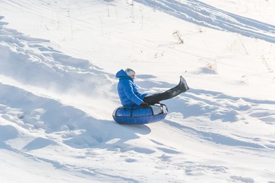 child snow tubing down slope