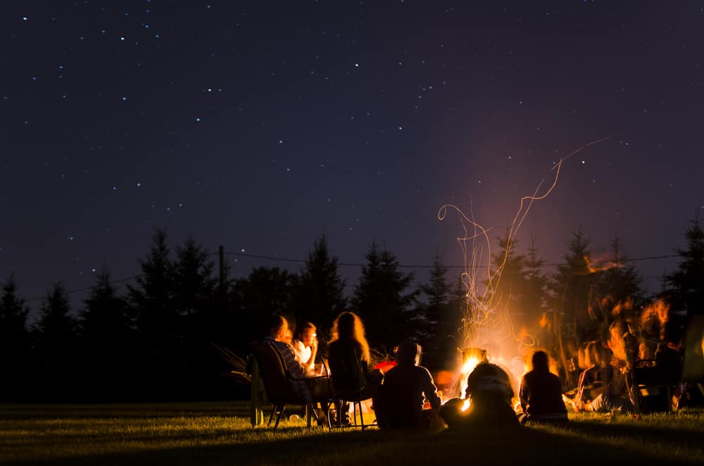 people sitting around campfire.