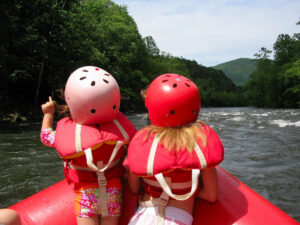 Two kids in the front of the raft on river