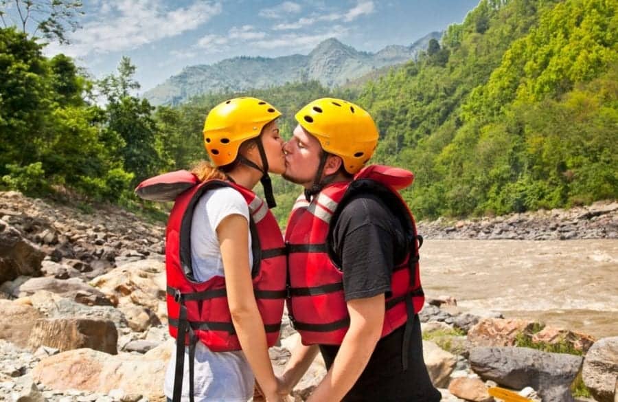 A couple kising in white water rafting gear