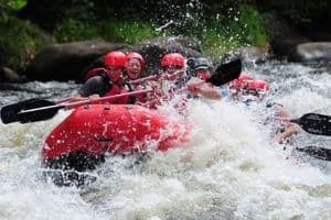 A group Smoky Mountains white water rafting with lots of splashing.