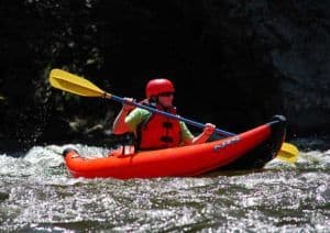 Happy kayaker in red kayak with yellow paddle on Pigeon River in the Smoky Mountains