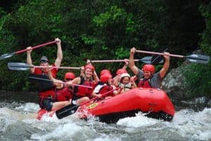 A Gatlinburg TN white water rafting group holding their paddles above their heads.