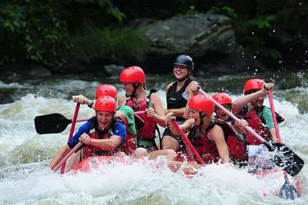 A happy group of friends white water river rafting on their Smoky Mountain vacation.