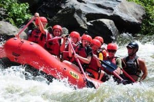 Group of happy people white water rafting down the river