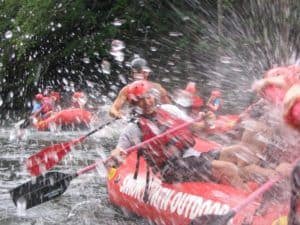 Man splashing water with his paddle while white water rafting