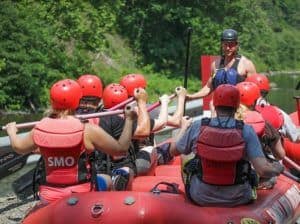 A rafting guide faces his passengers in his raft.