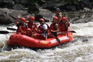 Family waving at camera while rafting