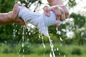 person wringing out a white cotton shirt full of water