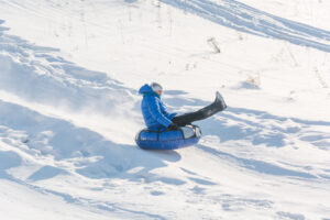 child snow tubing down slope