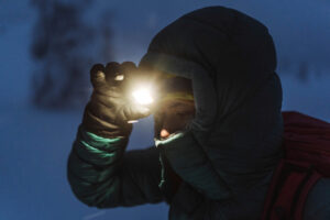 winter hiker turning on headlamp