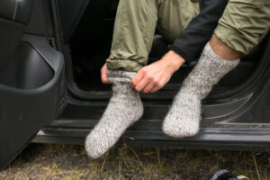 man putting on wool socks before hiking