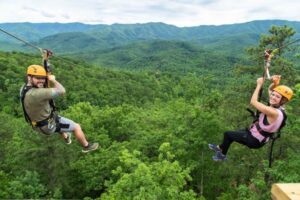 Two friends enjoying side-by-side mountaintop ziplines in the Smoky Mountains